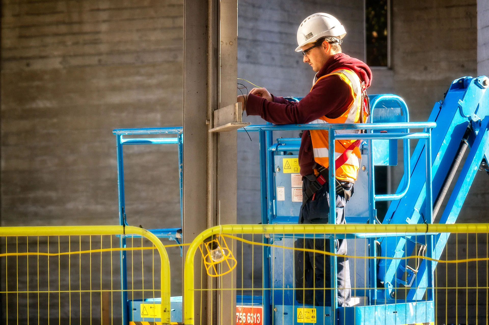 Electrician on a cherry picker fixing wiring in North Wales